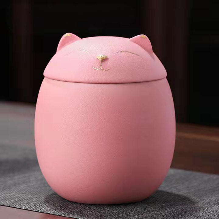 Pink cat-shaped urn on a dark surface