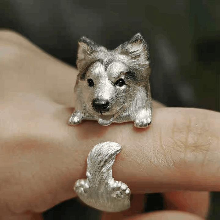 Silver dog-shaped ring on a finger with a blurred background